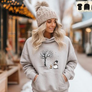 May include: A gray hoodie features a winter scene with a snowman, a small dog, and a tree. The hoodie has a large front pocket. Three black hoodies are shown in the upper right corner with the words 'Hoodie', 'Sweatshirt', and 'Pullover' printed on them. The text 'Choose your favorite from the drop-down menu' is also visible.